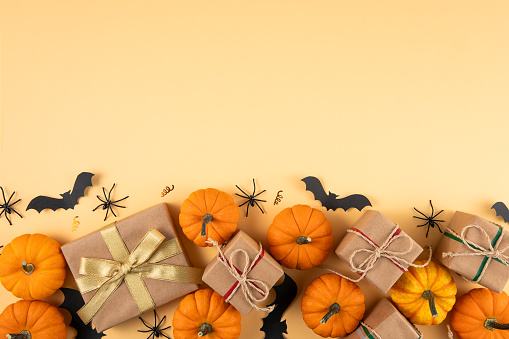 Halloween background with gift boxes and pumpkins on orange colored background