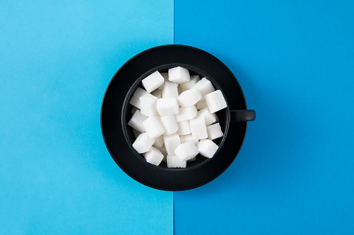 Sugar cubes in coffee cup on blue background