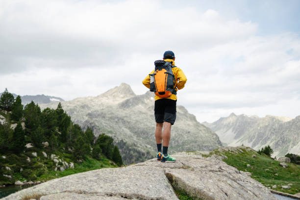 istock Young man standing on a rock with mountain background 1582475223