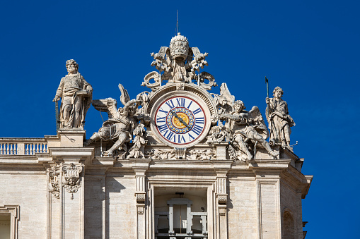 Vatican, Rome, Italy - October 9, 2020: Facade of  Saint Peter's Basilica with decorative clock on a top, on a background of blue sky