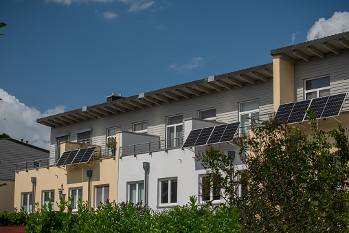 Panorama view of townhouses with with solar power plant on a balconies to generate green electrical energy for home. Balcony solar power station eco-friendly to use renewable energy.