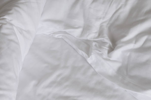 istock Texture of crumpled white bed sheets as background 1582508328
