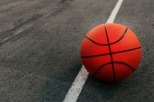 Basketball ball on outdoor court with asphalt surface, selective focus