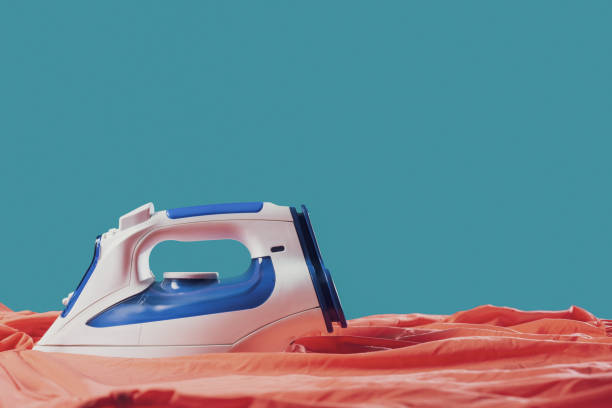istock Iron smoothing clothes on the ironing board 1582514344