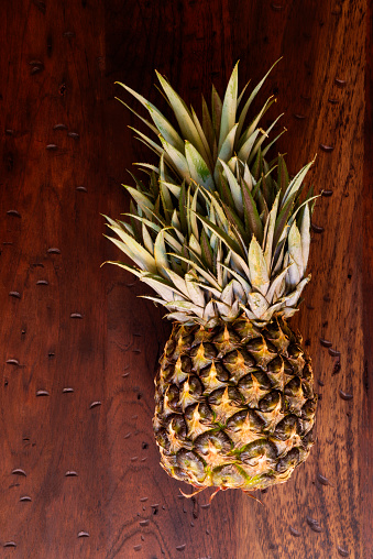 High angle view of pineapple fruit over a rustic wooden table in the kitchen at home. Delicious healthy food to eat as dessert at home .Image made with a full frame camera and 50 mm lens f-stop 1.4