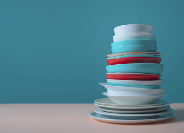 Pile of colorful clean dishes on light blue background