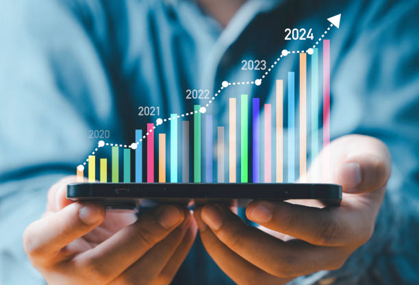 istock Businessman holding smartphone with virtual technical graph and chart for analysis stock market, technology investment and value investment concept. 1582521965