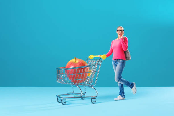 istock Tiny woman pushing a full shopping cart 1582523096