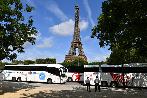 Paris, France-07 26 2023: Group of coach buses parked in front of the Eiffel tower in Paris, France.