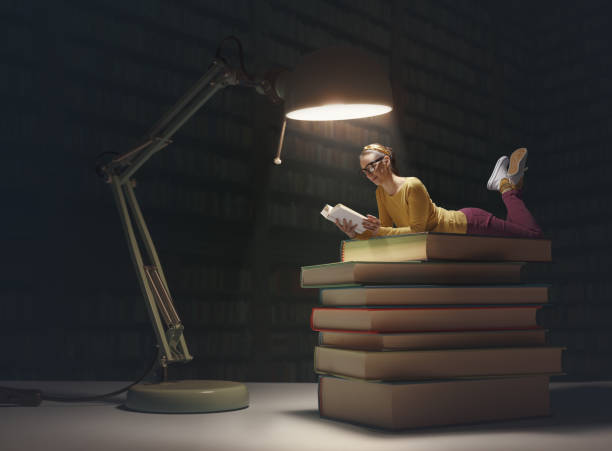 istock Tiny woman reading books in a dark library 1582527558
