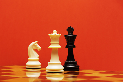 Top view on wooden chess board with figures during the game on white wooden table background