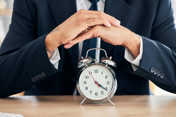 orologio, uomo d'affari e gestione del tempo in ufficio per scadenze, orari puntuali e fitti di impegni. mani di professionista o broker che lavorano alla scrivania con allarme, promemoria e timer per obiettivi e agenda - deadline personal organizer busy clock foto e immagini stock