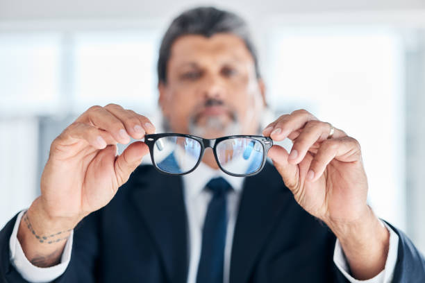istock Man, hands and holding glasses at work for vision, bluelight security and cleaning lens. Closeup, bokeh and a mature corporate employee with eyewear for eyes support, frame and help with eye care 1582543245