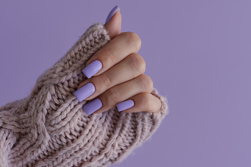 Uñas de color púrpura. Manicura gelish. Mano femenina con uñas delicadas de color lavanda de moda photo