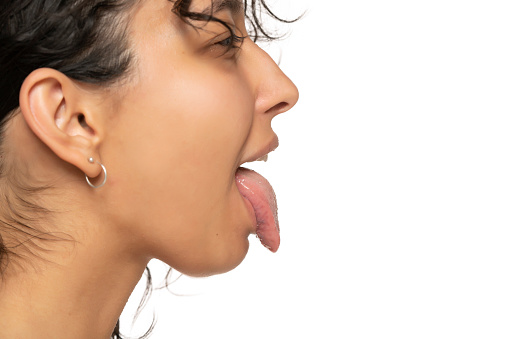 profile close up of young etnic woman with tongue out on a white studio background
