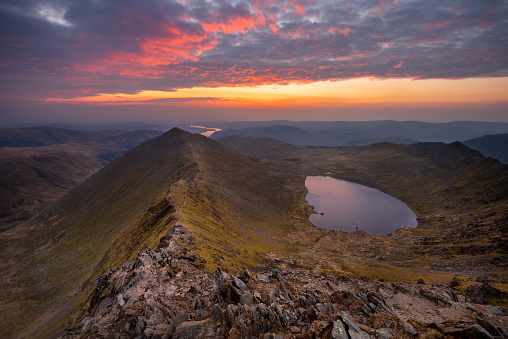 Breathtaking sunrise at the summit of Helvellyn; one of the Lake Districts most popular mountain hikes. Swirral Edge, Red Tarn and Ullswater can be seen in the background.