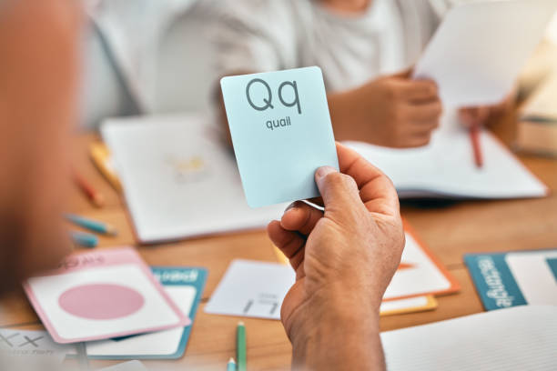 Learning, cards and parents with children and letter lesson for language, study and alphabet. School, homework and help with family at table and teaching for reading tutor, literacy and phonics