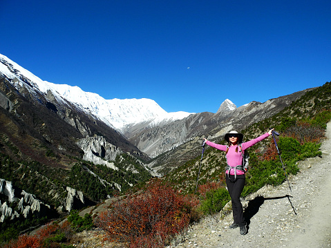 Young woman with wide spread hands facing the sun in Himalayas. Hiking and activity in Nepal.