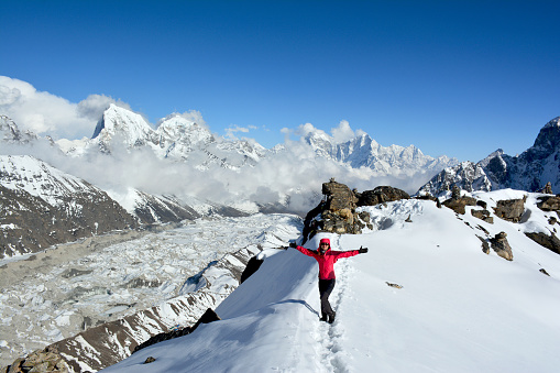 Woman with wide-spread arms on the mountain ridge in the Himalayas. Hiking and mountaineering in Nepal.
