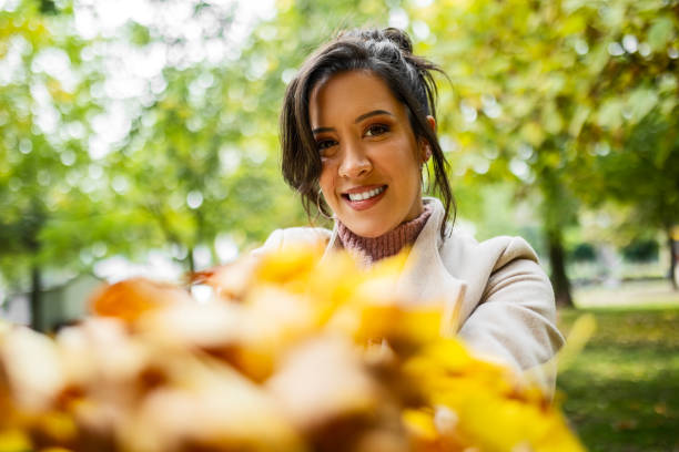 istock Young Woman's Playful Leaf Toss in Happiness 1582589358