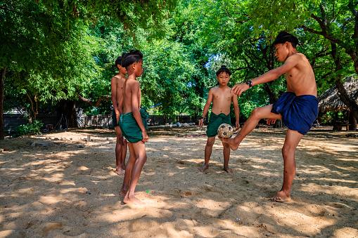 Burmese young boys with an ancient hairstyle playing chinlone (traditional game - cane ball) in the village near Bagan, Myanmar (Burma)