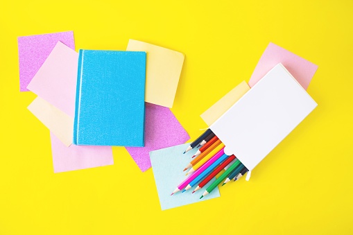 Back to school, books, colorful sticky notes and pencils on yellow background with copy space