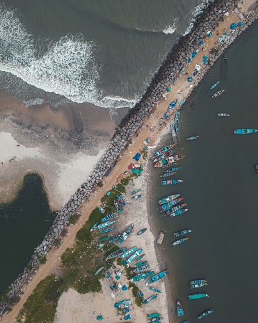 An aerial view of a rock jetty with boats resting nearby. Calicut, Kerala, India.