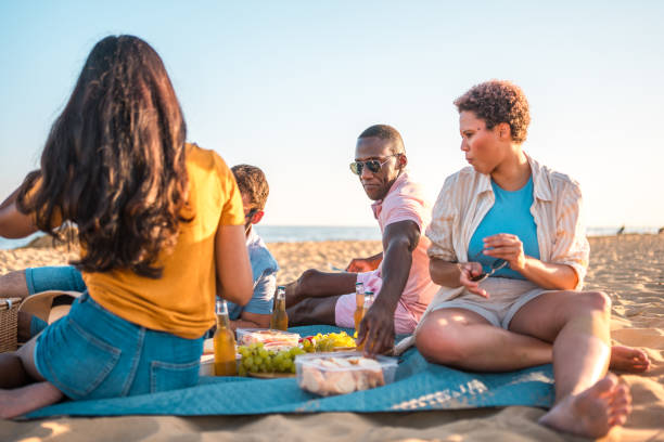 istock Cool Mixed Race Group Having a Sunset Picnic At The Beach 1582604906