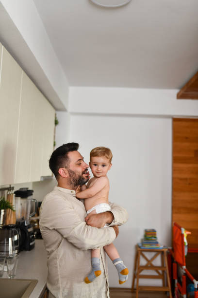 istock Father About To Kiss Baby Son While Holding Him In Kitchen 1582621375