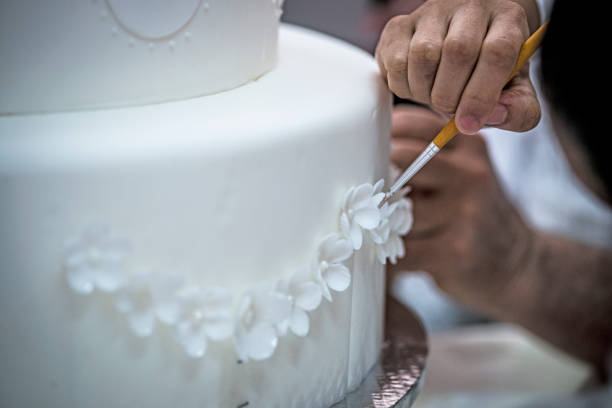 istock Pastry chef preparing a 3 tier frosted layered wedding cake. 1582639987