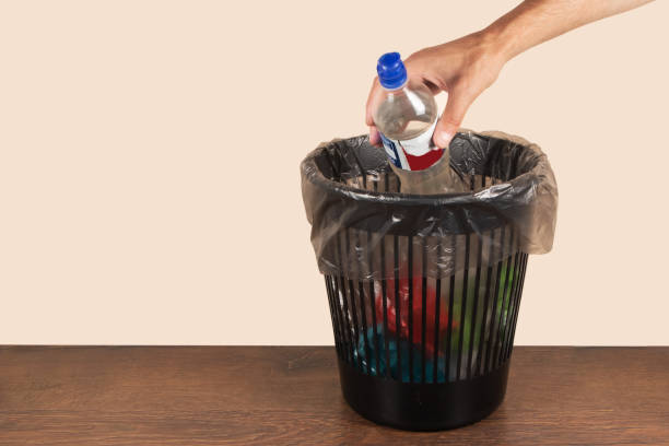 istock recycling, waste sorting and sustainability concept - hand throwing plastic bottle into trash can 1582646468