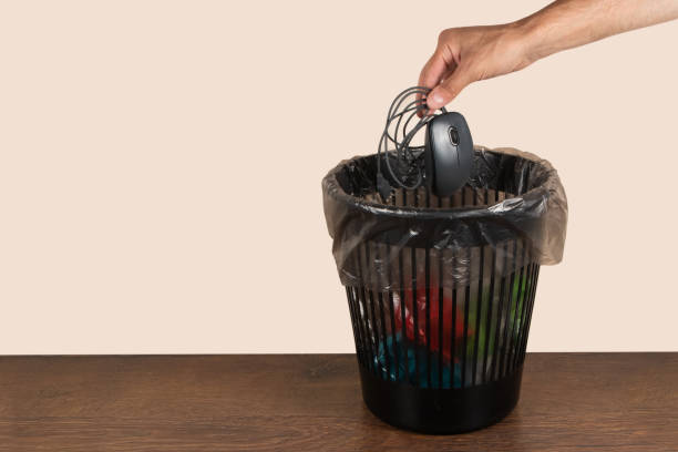 istock throwing a computer mouse in the trash bin, a computer mouse in hand in front of the trash bin, recycling plastic 1582646477