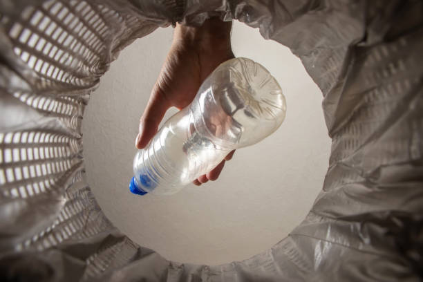 istock recycling, waste sorting and sustainability concept - hand throwing plastic bottle into trash can inside view 1582648156