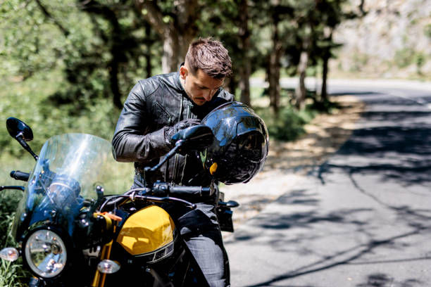 istock Handsome biker puts safety helmet 1582663745