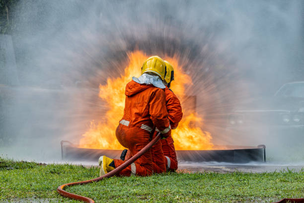 istock Firefighters wearing helmets with fire safety equipment Use Twirl aerosol fire extinguishers to fight oil flames.Preventing fire accidents is an industrial safety concept. 1582665973