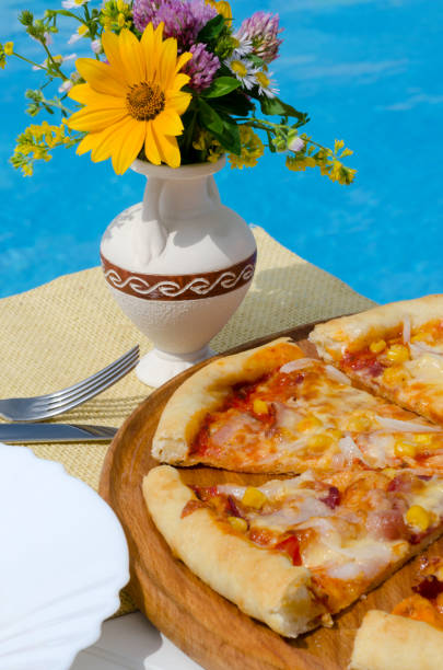 istock Pizza on a white plate against the backdrop of a blue pool. 1582673748