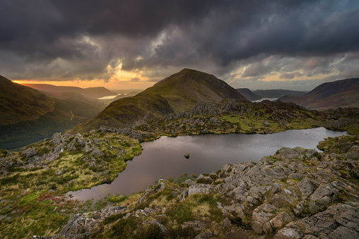 View of Haystacks Tarn overlooking Crummock Water and Ennerdale with dark forboding rain clouds in the sky. Lake District, UK.