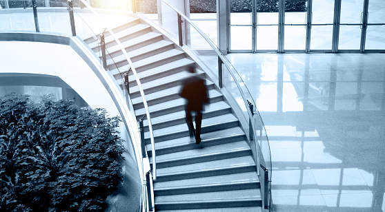 Single business man walking up stairs in office building