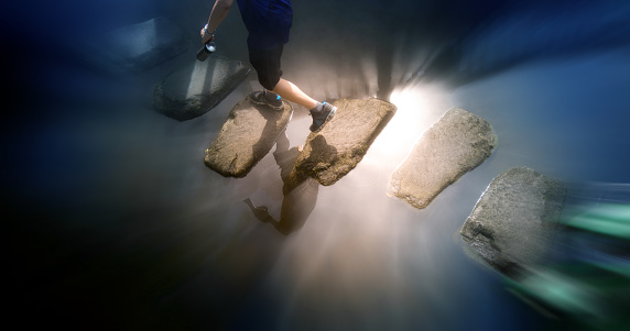 Top view of man across stepping stones to cross a stream