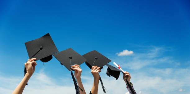 istock Many hands holding graduation hats against blue sky 1582695977