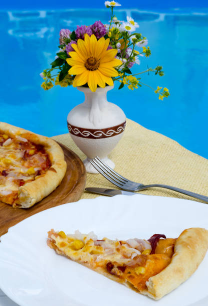Pizza on a white plate against the backdrop of a blue pool.