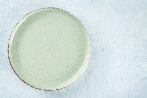 An empty green plate, overhead flat lay shot on a slate background, with copy space