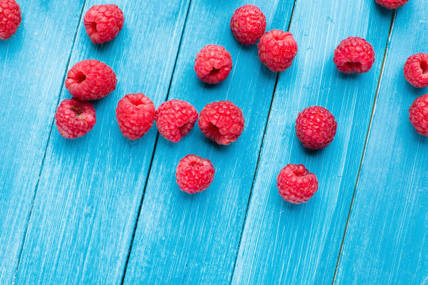 istock Ripe sweet raspberries on blue wooden background 1582728151