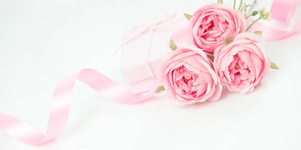 istock Three pink roses with ribbon and giftbox on the white table 1582742237