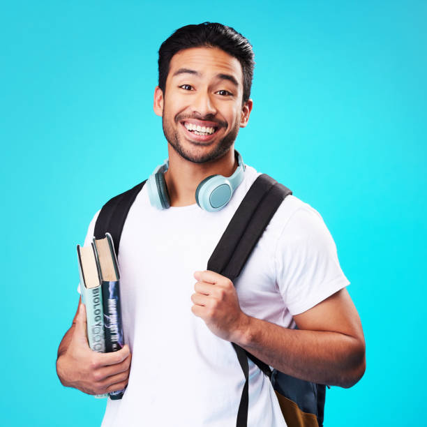 istock Indian, college student and portrait in studio with backpack for university, education and studying with books on blue background. Happy, man and person excited to study and learn for future goals 1582762268