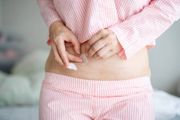 istock Abdomen of Asian woman. Applying hormone replacement patch 1582765431