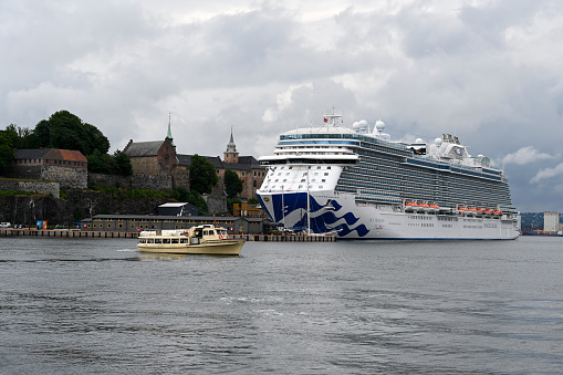 Oslo, Norway 0 August, 2019: Akershus Fortress/ Castle and  the AIDA Luna cruise ship in the harbor of Oslo. The castle was built around somewhere in the 1290's by King Haakon V. It has  functioned as a prison and a military base, currently it's also temporary housing for the Prime Minister.