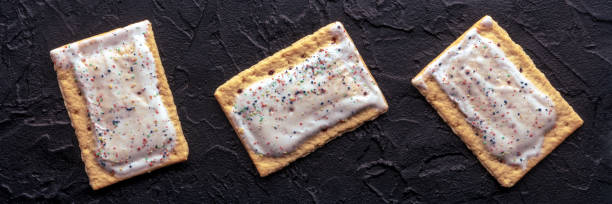 istock Pop tarts panorama. Poptart toaster pastry with icing on black 1582779725