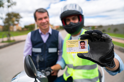 Happy Latin American man getting his driver's license after approving his motorcycle driving test and looking at the camera