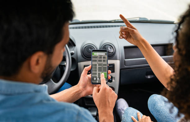 istock Couple driving a car and using the GPS app while pointing the road 1582801832